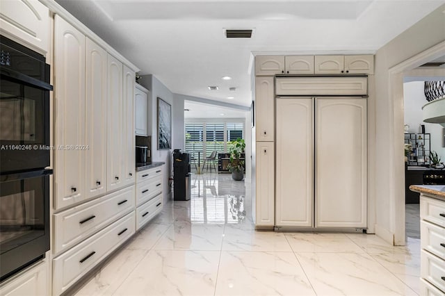 kitchen featuring paneled built in refrigerator, light tile patterned floors, and black double oven