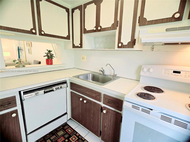 kitchen featuring sink, dark brown cabinetry, light tile patterned flooring, and white appliances