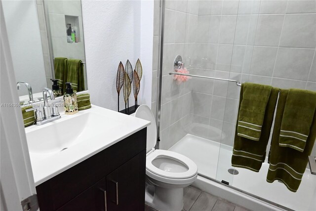 bathroom featuring toilet, a shower with door, and vanity