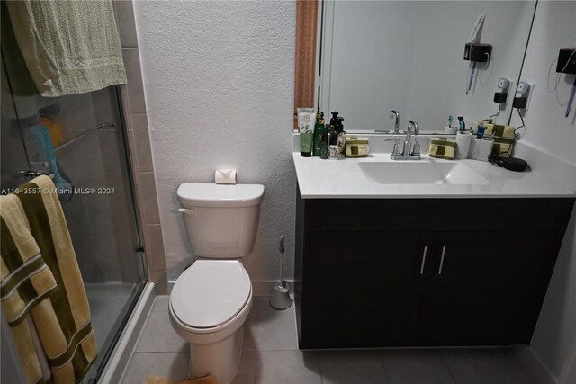 bathroom with vanity, toilet, tile patterned flooring, and a shower with door