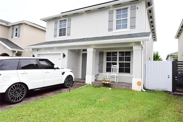 view of front of home featuring a garage, a porch, and a front yard