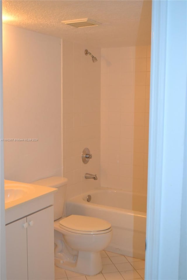 full bathroom featuring toilet, tile patterned flooring, vanity, a textured ceiling, and tiled shower / bath combo