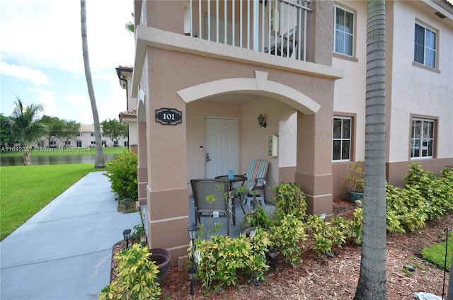 view of exterior entry featuring a balcony and a yard