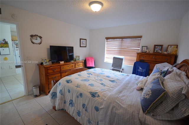 bedroom featuring light tile patterned flooring and white refrigerator