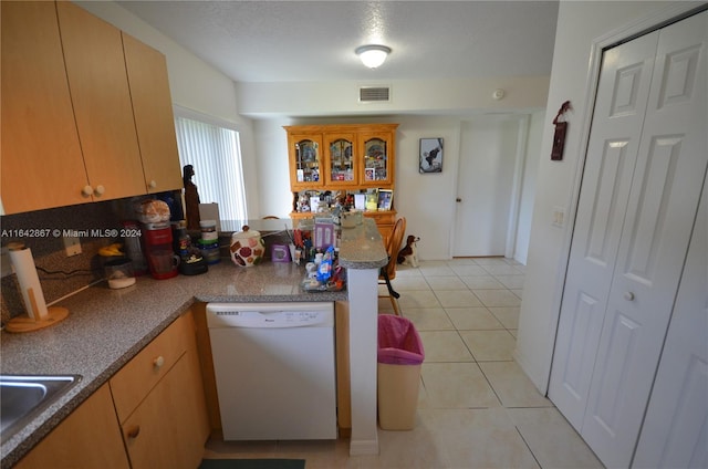 kitchen with sink, a textured ceiling, white dishwasher, kitchen peninsula, and light tile patterned flooring