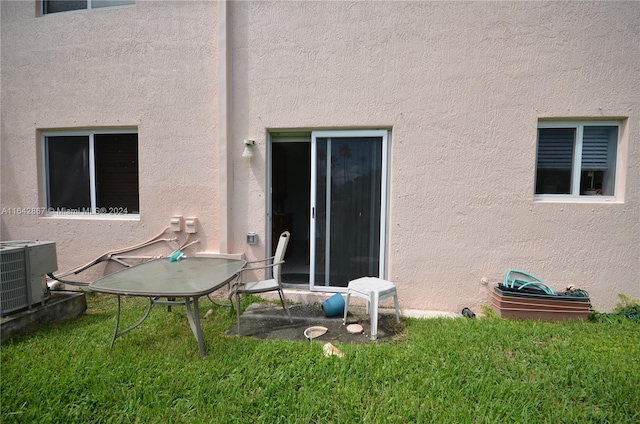 rear view of property with cooling unit and a lawn