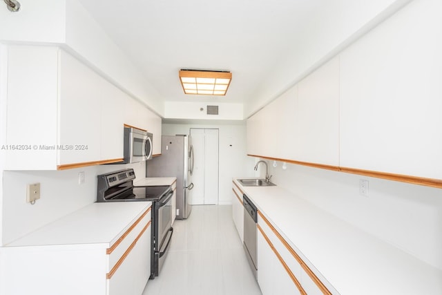 kitchen featuring appliances with stainless steel finishes, light tile patterned flooring, white cabinets, and sink