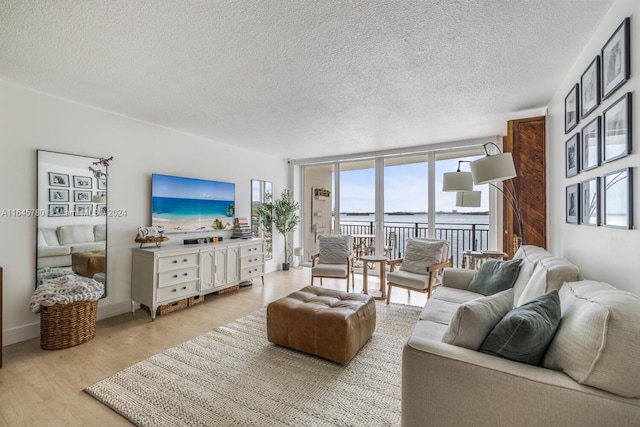 living room with a textured ceiling, light hardwood / wood-style flooring, and a wall of windows