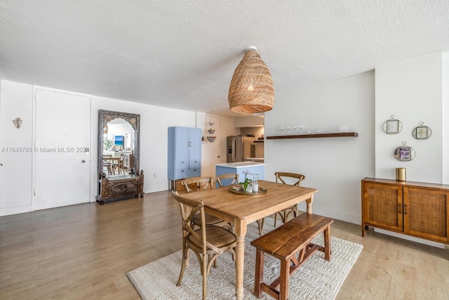 dining space featuring light wood-type flooring and a textured ceiling