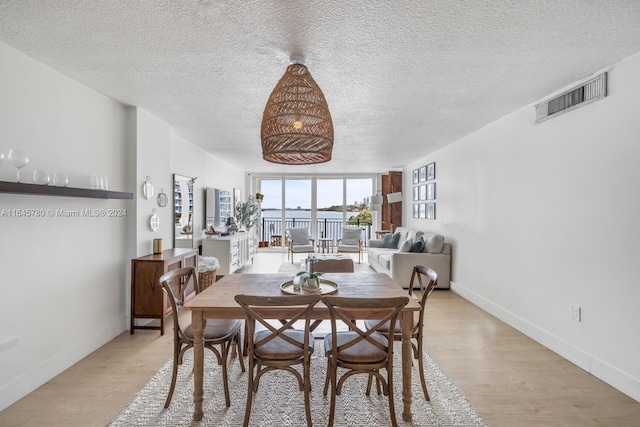 dining space with a textured ceiling and light hardwood / wood-style floors