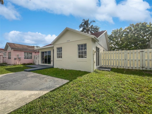 back of house featuring a patio area, fence, a lawn, and stucco siding