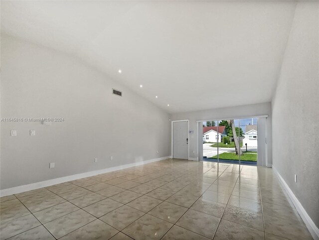 empty room with vaulted ceiling and light tile patterned floors