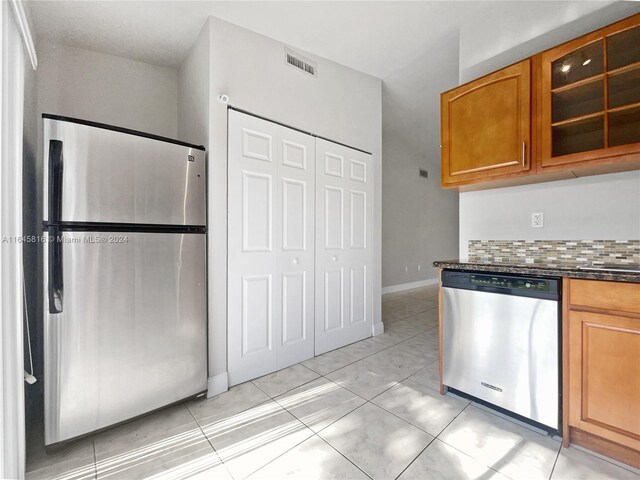 kitchen featuring decorative backsplash, light tile patterned flooring, and stainless steel appliances