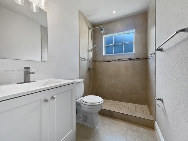 bathroom with toilet, vanity, tiled shower, and tile patterned floors