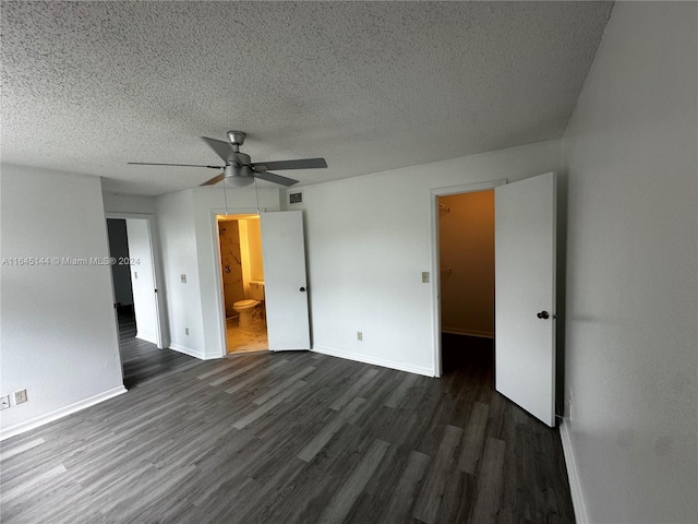 empty room with ceiling fan, dark hardwood / wood-style flooring, and a textured ceiling