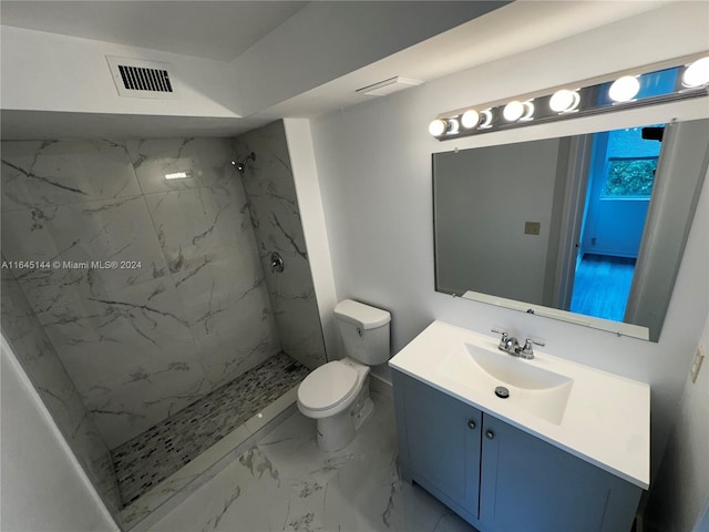 bathroom featuring vanity, toilet, and a tile shower