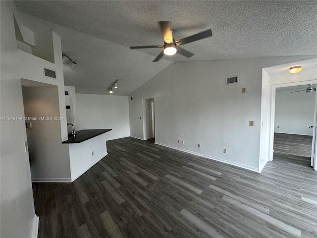 unfurnished living room with ceiling fan, dark hardwood / wood-style flooring, a textured ceiling, and vaulted ceiling