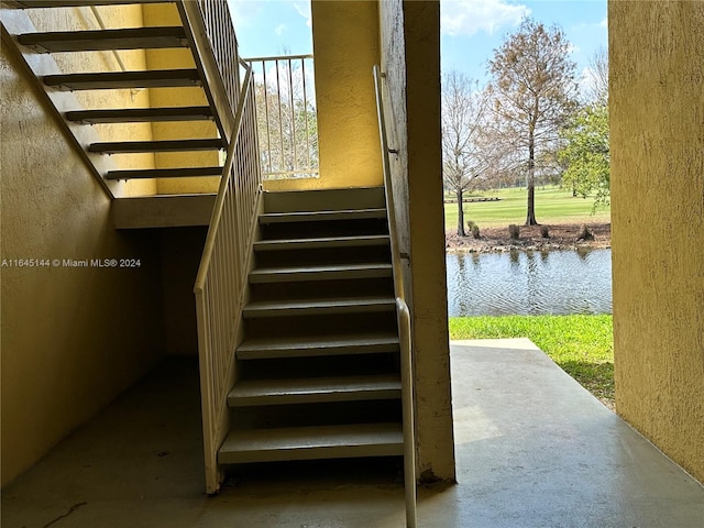 stairs with a water view, concrete flooring, and plenty of natural light