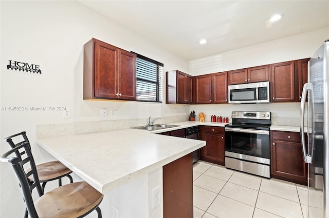 kitchen with kitchen peninsula, a breakfast bar area, light tile patterned flooring, sink, and stainless steel appliances