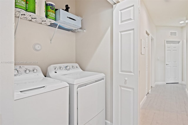 washroom with washing machine and dryer and light wood-type flooring