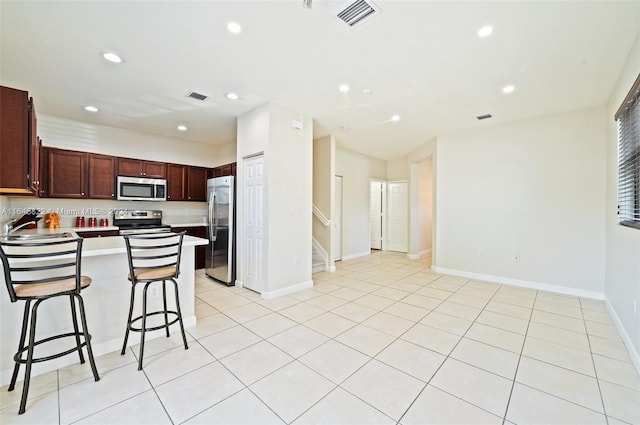 kitchen with appliances with stainless steel finishes, sink, a kitchen island, a breakfast bar area, and light tile patterned floors