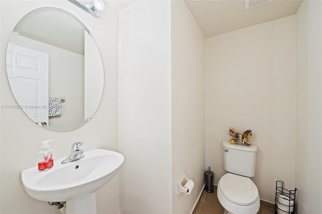 bathroom with toilet, tile patterned floors, and sink