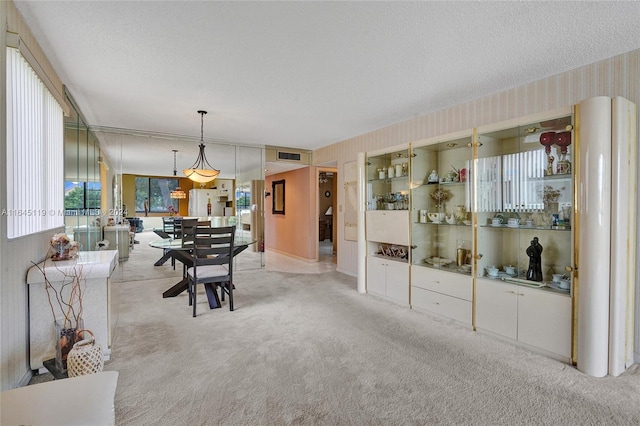 dining space featuring light colored carpet and a textured ceiling