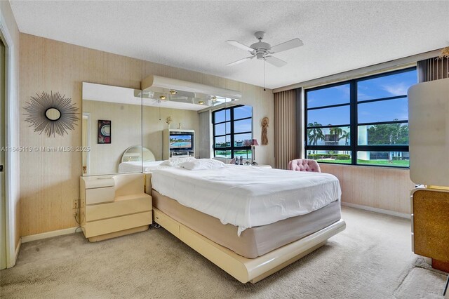 carpeted bedroom featuring multiple windows, a textured ceiling, and ceiling fan