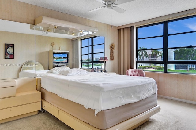 bedroom with carpet flooring, ceiling fan, wooden walls, and a textured ceiling