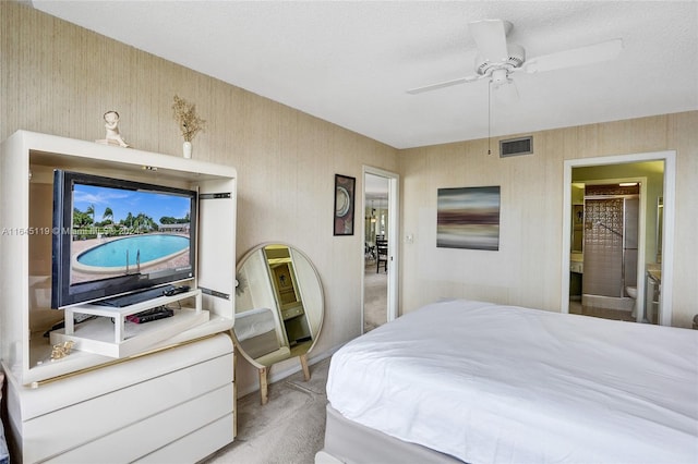 bedroom featuring light carpet, a textured ceiling, ensuite bathroom, and ceiling fan