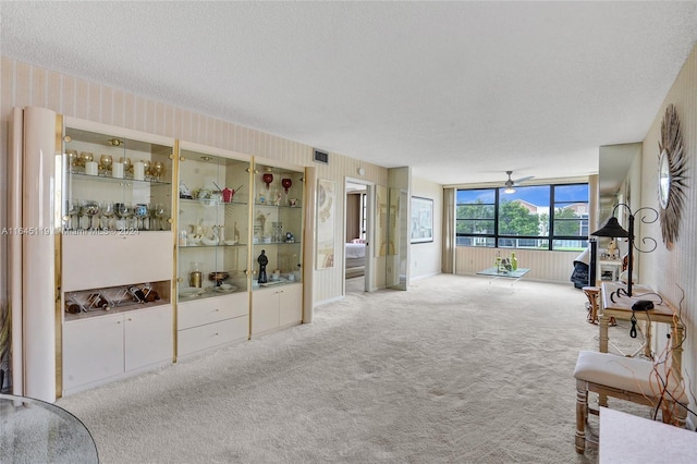 carpeted living room with ceiling fan and a textured ceiling