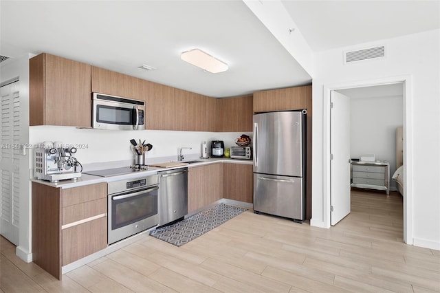 kitchen featuring stainless steel appliances, sink, and light wood-type flooring