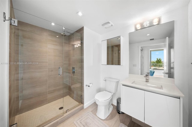 bathroom with a shower with shower door, toilet, and vanity