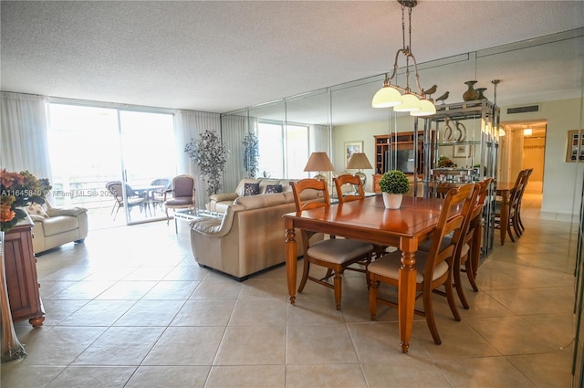 dining space with light tile patterned floors, a textured ceiling, and a wall of windows