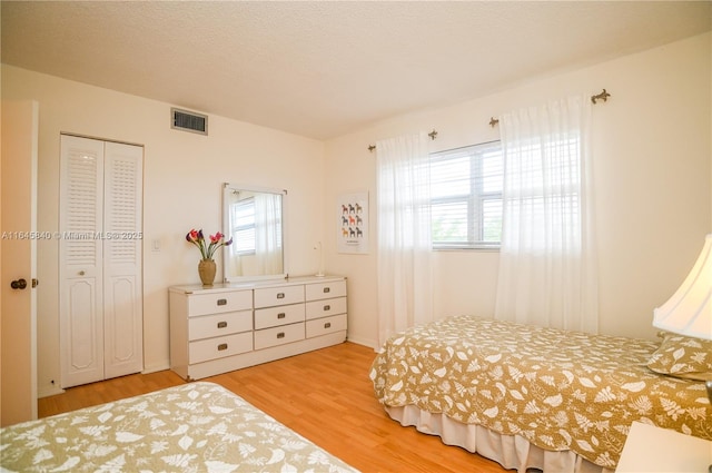 bedroom featuring multiple windows, light hardwood / wood-style flooring, and a closet