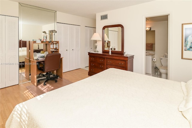 bedroom with multiple closets, ensuite bathroom, and light hardwood / wood-style floors