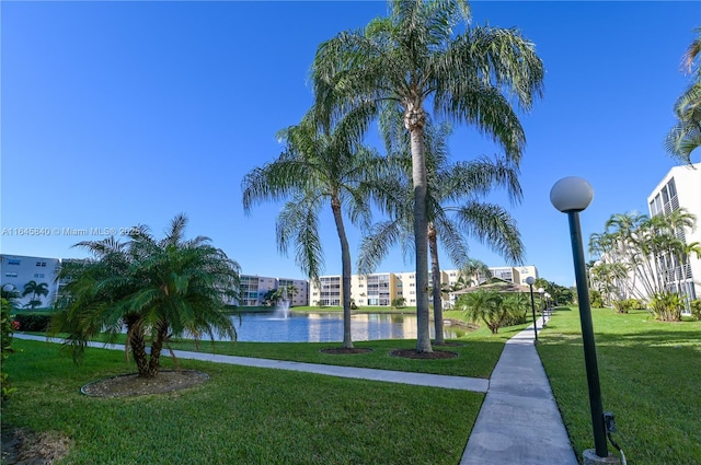 view of home's community with a water view and a lawn