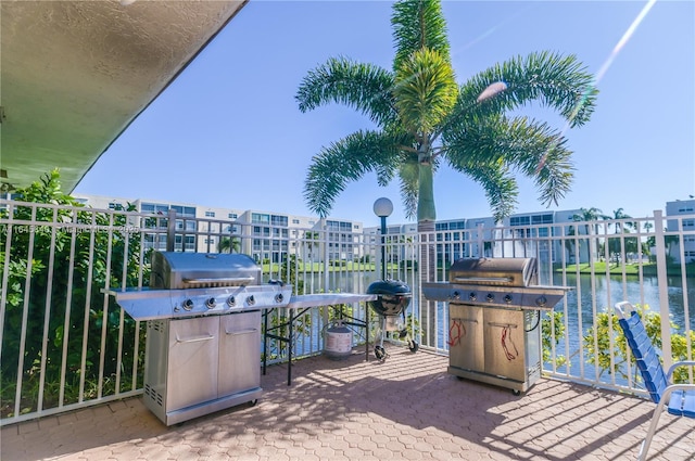 view of patio / terrace featuring a grill, a water view, and a balcony