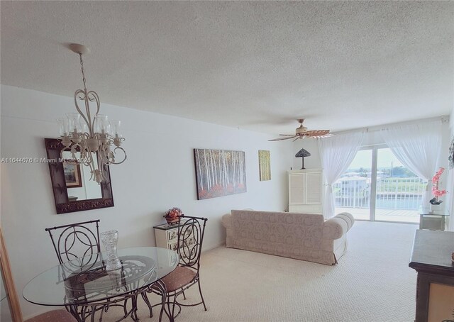 carpeted living room featuring ceiling fan with notable chandelier and a textured ceiling