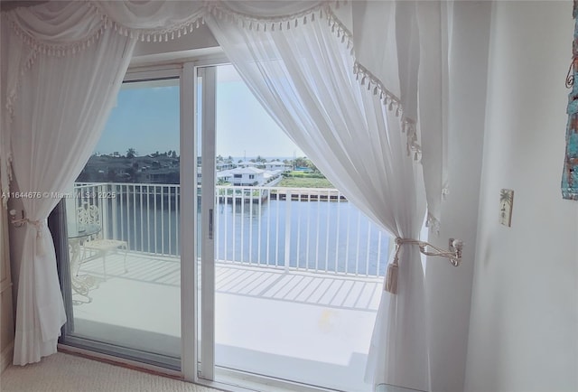 doorway to outside with a water view and carpet flooring