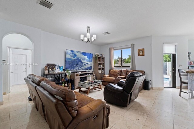 living room featuring light tile patterned flooring, a notable chandelier, and a textured ceiling