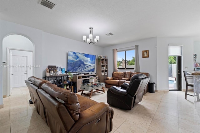 living area with arched walkways, visible vents, a textured ceiling, and an inviting chandelier