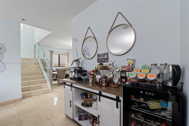 interior space featuring wine cooler, light tile patterned flooring, visible vents, baseboards, and stairway