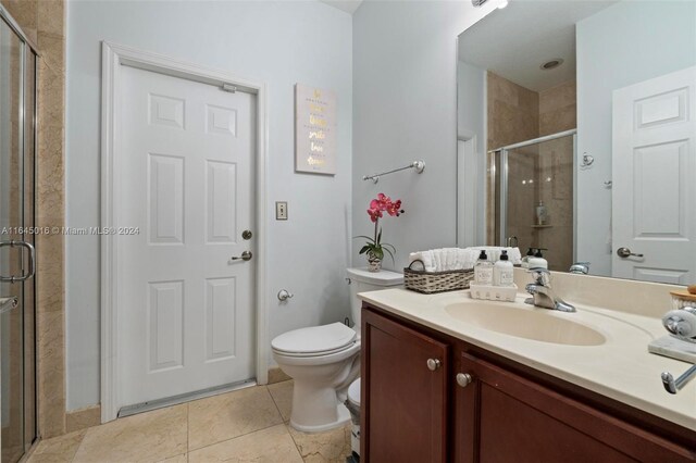 bathroom with tile patterned flooring, an enclosed shower, toilet, and vanity