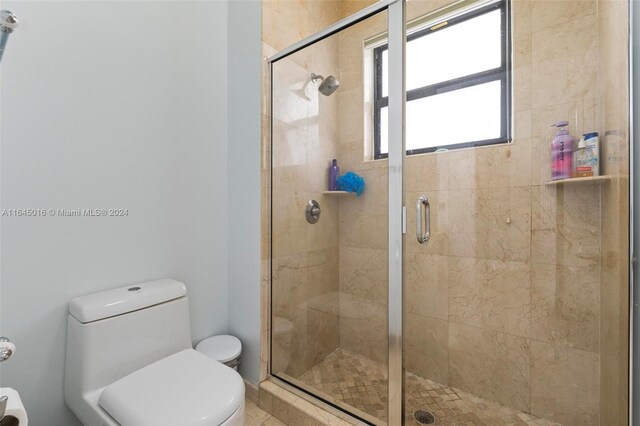 bathroom featuring toilet and a shower with shower door