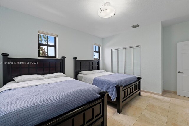 tiled bedroom with a closet and multiple windows