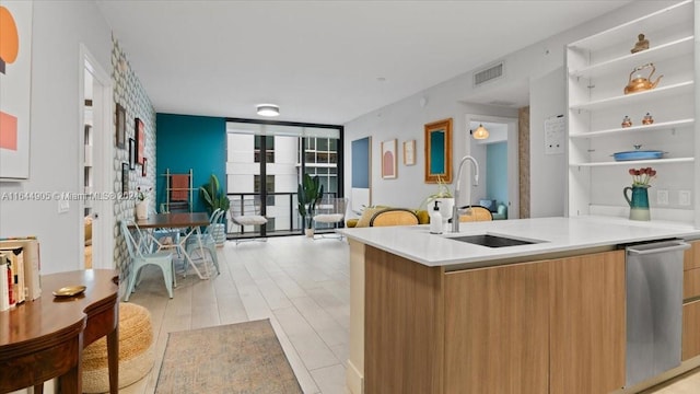 kitchen with expansive windows, sink, light wood-type flooring, and dishwasher