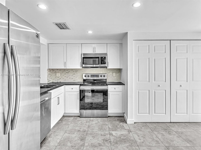 kitchen featuring backsplash, stainless steel appliances, white cabinetry, and light tile patterned floors