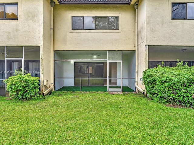 rear view of house featuring a sunroom and a lawn