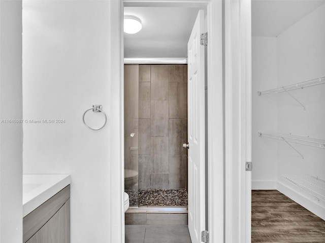 bathroom featuring hardwood / wood-style floors, toilet, walk in shower, and vanity